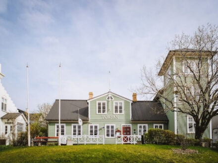 The charming exterior of Torfan Restaurant in Reykjavik, featuring its green facade and white trim.