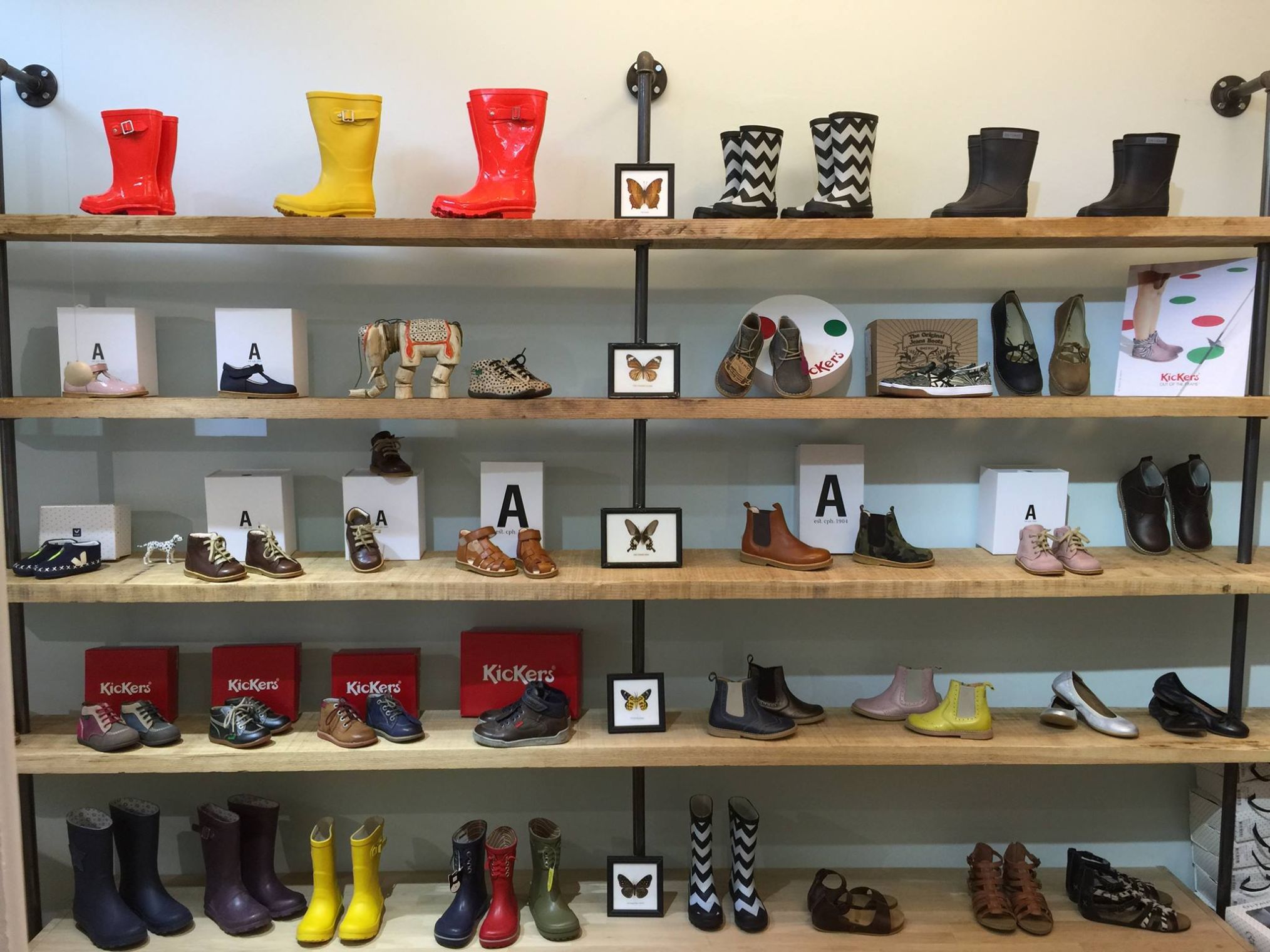 Interior view of Fló shoe store with multiple shelves displaying a wide variety of children's and adult footwear, including boots and shoes.