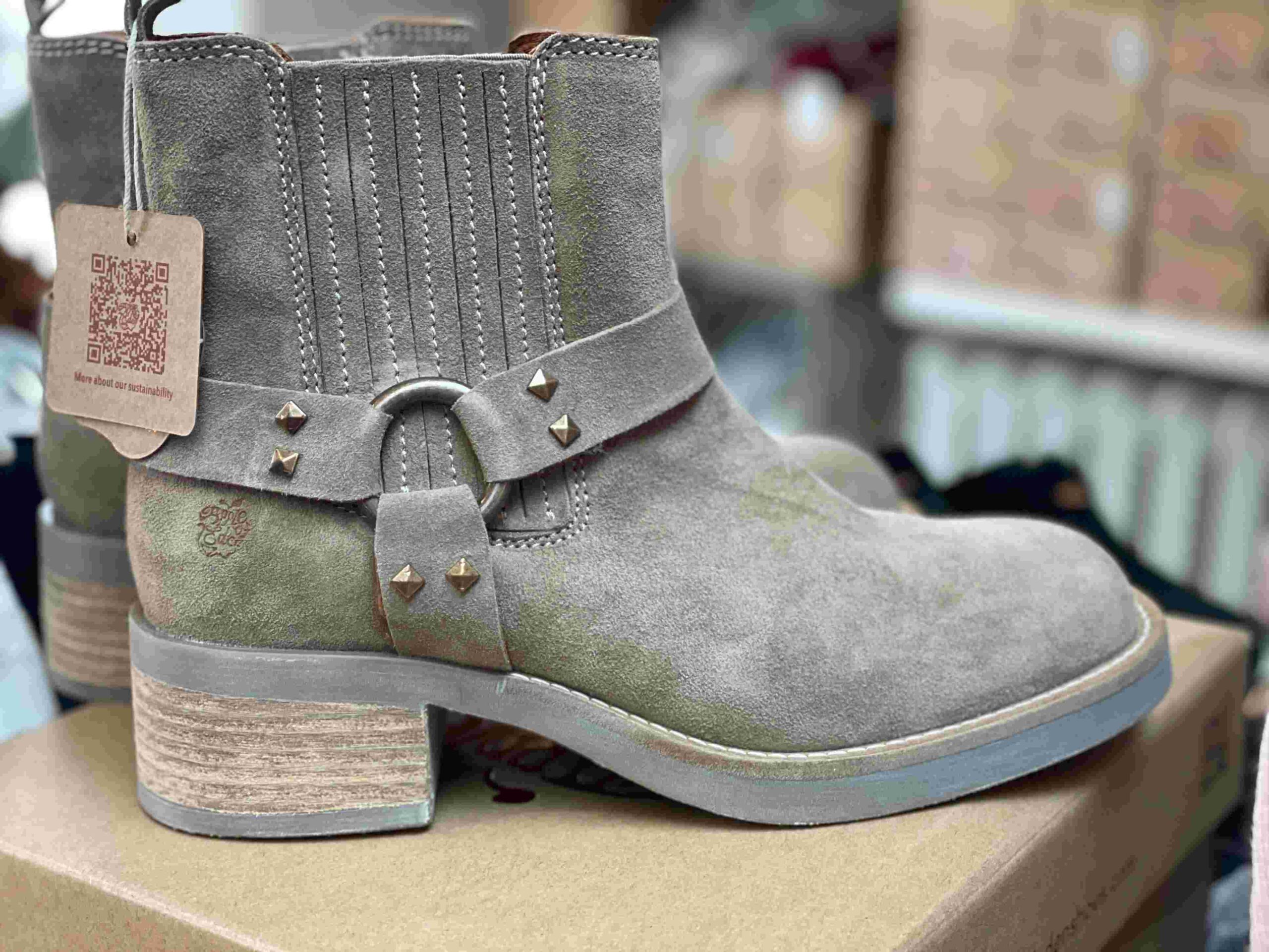 Close-up of a stylish light gray studded women's ankle boot displayed at Fló shoes.