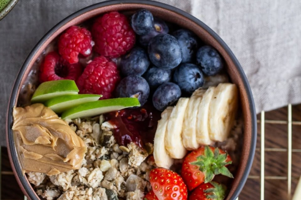 A healthy and colorful bowl of oatmeal topped with fresh berries, banana, apple slices, and peanut butter at Hygge Coffee and Micro Bakery in Reykjavik.