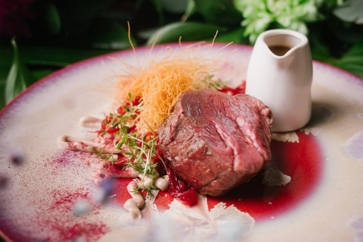 A close-up of an elegantly plated tenderloin steak at Kol Restaurant in Reykjavik, highlighting the artistic arrangement of the food and sauce.