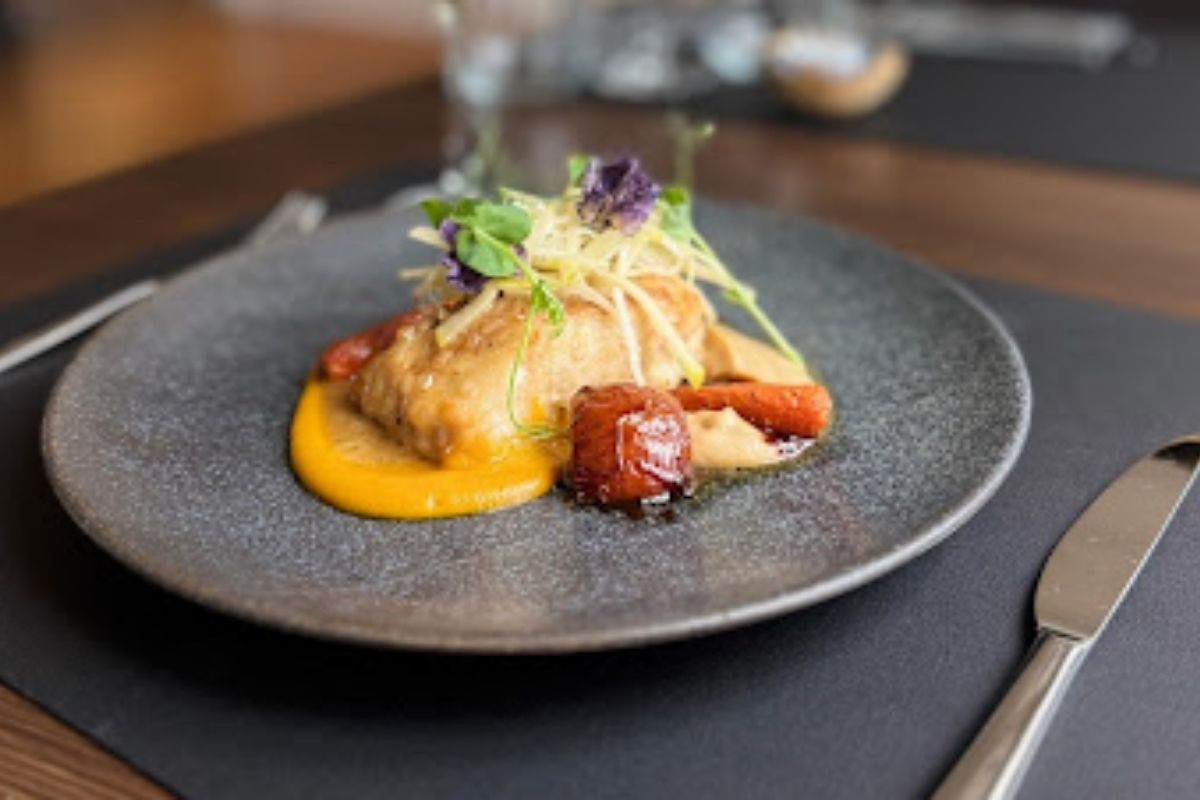 A beautifully plated pan-fried fish dish with colorful vegetables and sauce at Torfan Restaurant in Reykjavik.