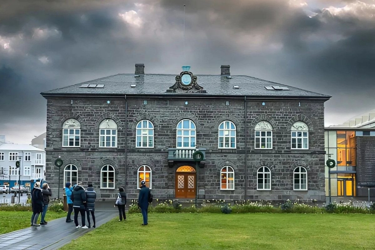 A group of people standing outside the Althingi building, the Icelandic Parliament, with 