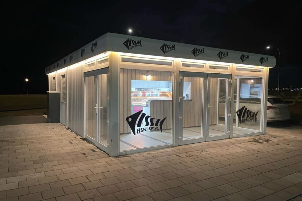 An illuminated Issi Fish & Chips storefront at dusk, showcasing its contemporary design and inviting ambiance for customers.