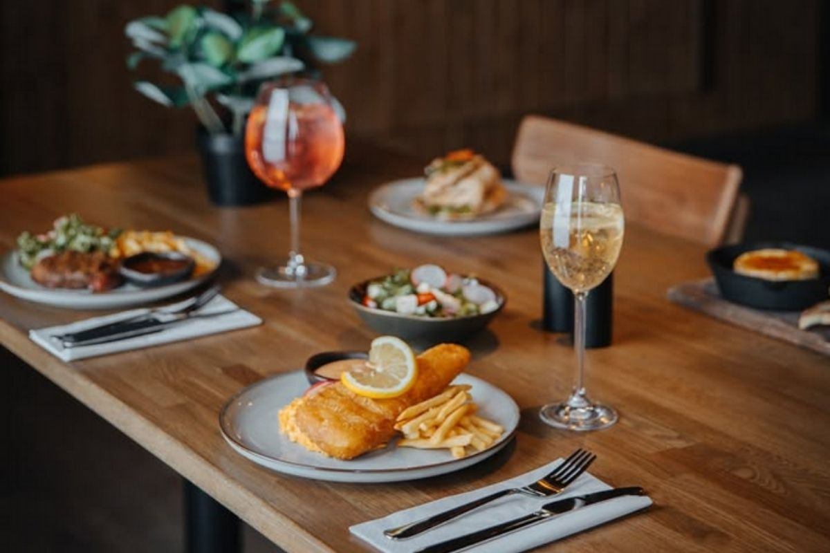 A delicious meal at Public Deli, featuring golden-fried fish and chips with a lemon wedge, alongside various other plates and drinks, in a restaurant setting.