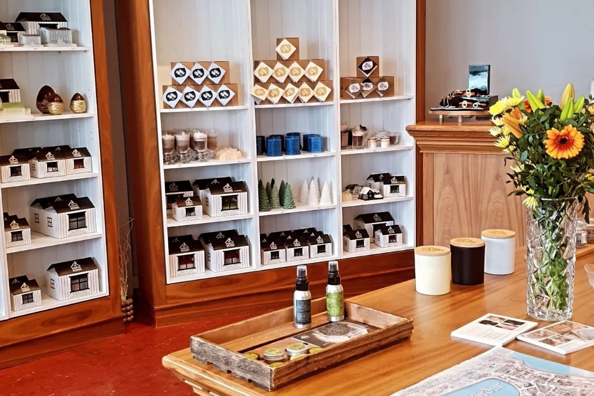 Kertahúsið, an Icelandic candle and gift shop, showcasing artisan candles, miniature house decor, and other boutique items on white shelving units and a wooden display table.