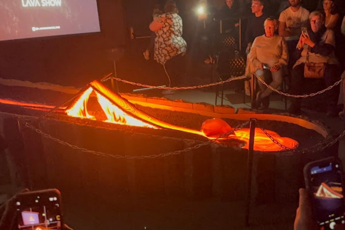 Molten lava flowing and pooling in an exhibit area, with an audience watching in the background.