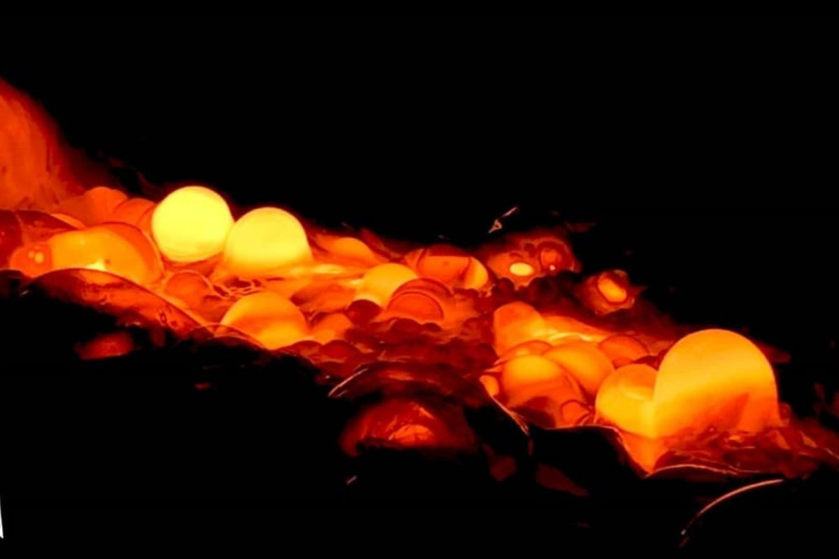 Close-up of glowing, orange and yellow molten lava bubbles and streams.
