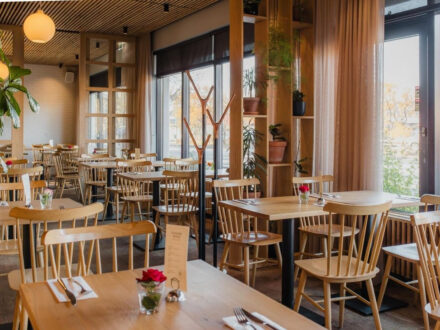 A cozy and well-lit dining area at Matkráin, with modern wooden furniture, elegant curtains, and natural light streaming through the windows.